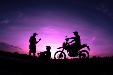 Silhouette of a motorcyclist and his dog on sunset backgroundの写真素材