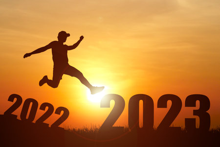 Silhouette of a man jumping over the number 2022 to celebrate the new year.の写真素材