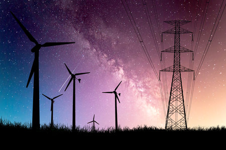 Silhouettes of wind turbines and power lines against a starry night sky with a colorful sunset backdrop.の写真素材