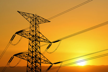 Silhouette of a transmission tower and power lines at sunset, showcasing the beauty of industrial structures against a colorful sky.の写真素材