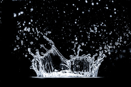 Stunning high-speed photograph of a water splash with droplets suspended in mid-air against a black background.の写真素材