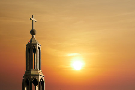 A serene sunset with a church steeple and cross silhouetted against a golden sky, capturing a moment of tranquility and spiritual reflection.の写真素材