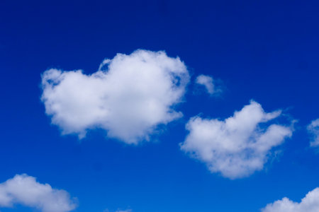 A serene image of fluffy white clouds floating in a clear blue sky, perfect for backgrounds, nature...