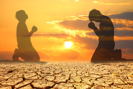 Silhouette of monk praying on dry land with sunset sky backgroundの写真素材