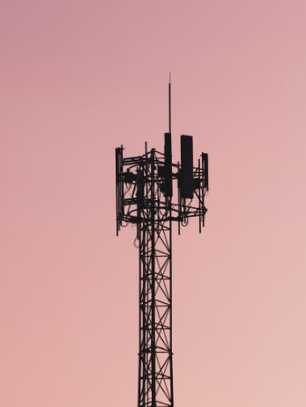 A communication tower silhouetted against a pink sunset sky, symbolizing modern technology and global connectivity.の写真素材