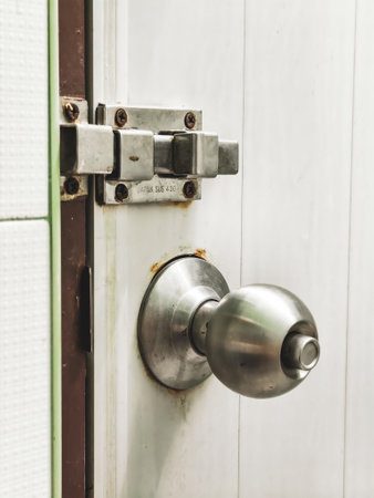 Detailed image of a stainless steel door knob and lock on a white wooden door, highlighting home security and interior design.の写真素材