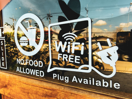 Window signage at a cafe showing free WiFi availability and no food policy, with reflections of the outside environment.の写真素材