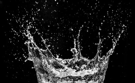 High-speed capture of water splash against a black background, showcasing fluid motion and dynamic energy.の写真素材