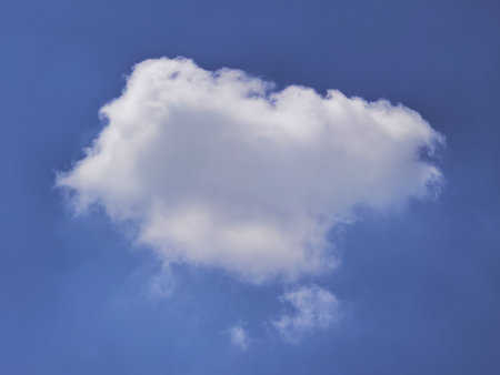 A single fluffy white cloud floats in a clear blue sky, symbolizing tranquility and simplicity.の写真素材