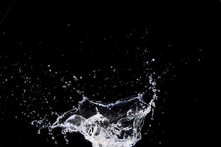 High-speed capture of water splash against a black background, showcasing dynamic motion and energy.の写真素材