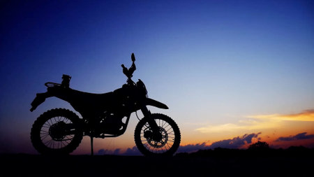 A striking silhouette of a motorcycle set against a colorful sunset, highlighting the dramatic sky and clouds.の写真素材