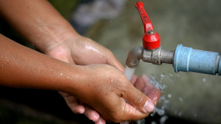 Hands washing with tap water in the public park, Thailand.の写真素材