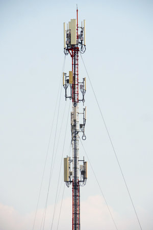 A tall communication tower with antennas against a clear blue sky, symbolizing modern telecommunication and wireless technology.の写真素材