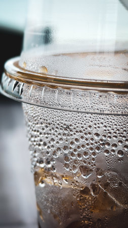 Detailed view of a cold drink in a plastic cup, showcasing condensation droplets on the surface.の写真素材