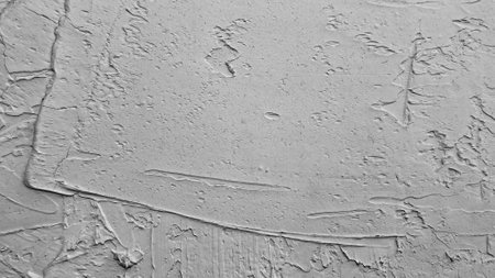 Close-up of a textured gray concrete wall showcasing abstract patterns and rough details, ideal for...