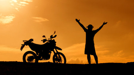 Silhouette of a woman on a motorbike at sunset.の写真素材