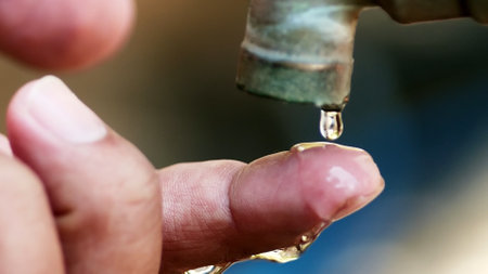 Close up of a man's hand holding a drop of water.の写真素材