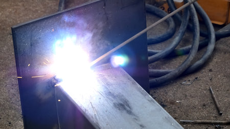 Detailed view of welding with bright sparks illuminating metal in an industrial workshop environment.の写真素材