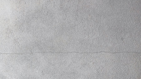 High-resolution image of a gray concrete wall with a subtle crack, perfect for backgrounds or design projects.の写真素材