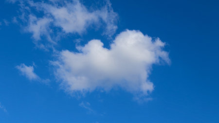 A single fluffy white cloud floats in a bright blue sky, symbolizing peace and serenity.