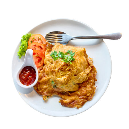 Tasty Thai omelette served with fresh vegetables and sauce, presented on a white plate with a fork.