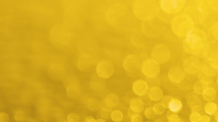 Vibrant yellow bokeh background featuring soft, circular light patterns ideal for creative design and artistic projects.の写真素材