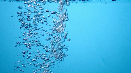 Close-up of bubbles rising in clear blue water, capturing a refreshing and tranquil underwater scene.の写真素材