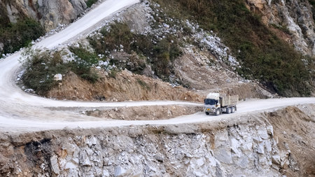 A large truck maneuvers through a steep, winding road in a rocky quarry, showcasing industrial transport in a challenging terrain.の写真素材