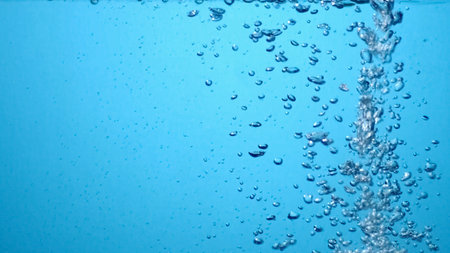Close-up of bubbles rising in clear blue water, capturing a refreshing and invigorating scene.の写真素材