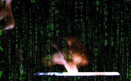 Blurred hands typing on a tablet with green digital code overlay, creating a futuristic matrix effect in a dark setting.の写真素材