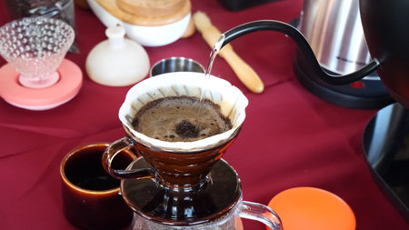 Close-up of pour over coffee brewing with a dripper and kettle, showcasing the art of manual coffee making.の写真素材