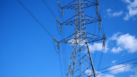 A towering electrical transmission structure set against a vibrant blue sky, showcasing modern energy infrastructure.の写真素材