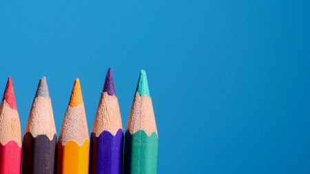 A row of colorful pencils on a bright blue background, perfect for themes of creativity, education, and art.の写真素材