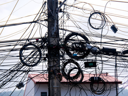 A tangled mass of power lines on a utility pole, illustrating urban infrastructure and complexity.の写真素材
