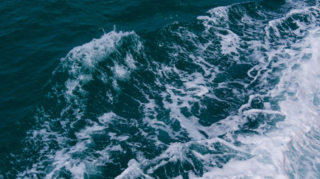 Aerial view of powerful ocean waves with white foam patterns on a deep blue sea, showcasing nature's dynamic beauty.の写真素材