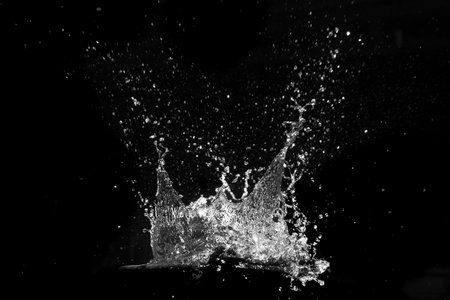 High-contrast image of water splashing, frozen in time against a black background, showcasing fluid dynamics.の写真素材