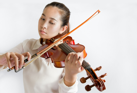 Beautiful young woman playing violin over white backgroundの写真素材