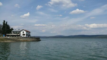 White house on the side of a lake with mountain visible in the farの素材