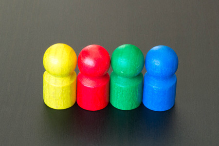 Red, yellow, green and blue figures on a black wooden backgroundの写真素材