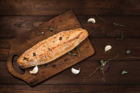 Ciabatta with olives, herbs and garlic on wooden backgroundの写真素材
