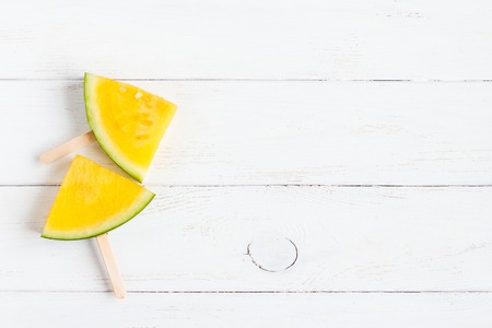 popsicle, yellow watermelon slices on sticks on wooden white background, flat lay, top viewの写真素材