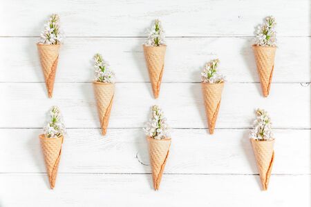 lilac flowers in ice cream cone on white wooden background, flat lay, top viewの写真素材