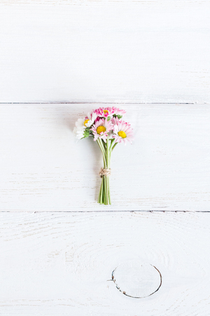 bouquet of daisy flowers on wooden white background, top view, flat layの写真素材