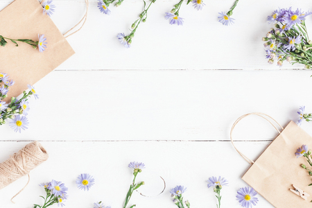 Flowers composition. Gifts and wildflowers on wooden white background. Flat lay, top viewの写真素材