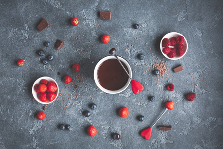 Chocolate fondue with fresh berries on dark background. Valentine's Day. Flat lay, top viewの写真素材