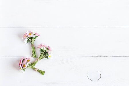 bouquet of daisy flowers on wooden white background, top view, flat layの写真素材