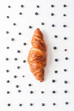 croissant and fresh blueberry on white wooden background, breakfast, top view, flat layの写真素材