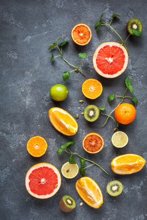 Colorful fresh fruit on dark background. Orange, tangerine, lime, kiwi, grapefruit. Fruit background. Summer food concept. Flat lay, top viewの写真素材