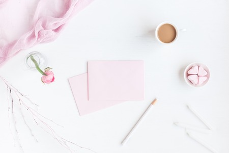 Feminine workspace with notebook, cup of coffee, paper blank, pink flower, pencil. Business concept. Flat lay, top viewの写真素材