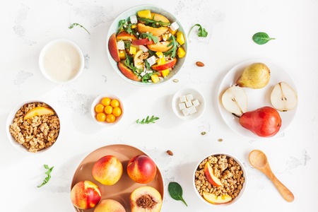 Breakfast with muesli, peach salad, fresh fruit, yogurt on white background. Healthy food concept. Flat lay, top viewの写真素材